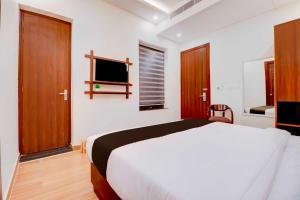 a bedroom with a white bed and a television at Collection O FRI Dehradun Hotel EL Portrait in Dehradun