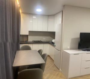 a kitchen with a table and chairs and a refrigerator at Центр тріо2 in Kamianets-Podilskyi +6 photos