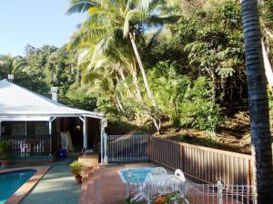 uma casa com piscina e palmeiras em The Islands Inn Motel em Airlie Beach
