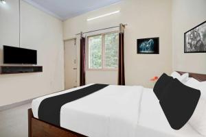 a bedroom with a white and black bed and a television at Collection O Mysore Shri Lakshmikantha Swamy Temple in Mysore