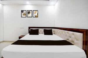 a bedroom with a large white bed with black pillows at Collection O Gorakhpur Industrial Area Shaurya Inn in Pipra