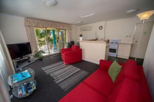a living room with a red couch and a kitchen at Beaches Serviced Apartments in Nelson Bay