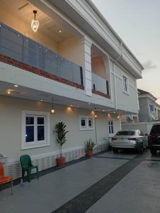 ein großes weißes Haus mit einem Auto auf einem Parkplatz in der Unterkunft Vitaluxury apartment 2 in Akowonjo