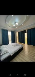 a bedroom with a large bed with blue curtains at Milano Garden Plaza Samarkand in Samarkand