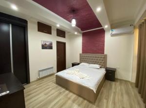 a bedroom with a bed and a purple wall at Milano Garden Plaza Samarkand in Samarkand