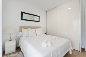 Un dormitorio blanco con una cama blanca y un espejo. en Sun Garden, en Adeje