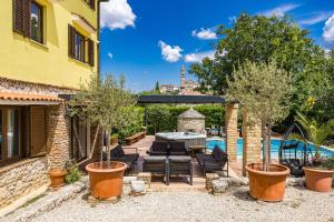 un patio avec une table et des chaises à côté d'une piscine dans l'établissement Villa Bucks near Poreč for 20 persons with Sea View, Whirlpool, Sauna & Fitness, à Višnjan