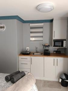 a kitchen with white cabinets and a sink and a bed at Crompton Studio Apartment 786 in Durban
