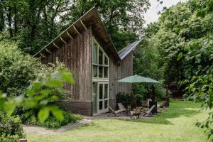 a house with chairs and an umbrella in the yard at de Wever Lodge in Otterlo