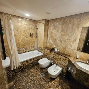 a bathroom with a tub and a toilet and a sink at Tulip Creek Hotel Apartments in Dubai
