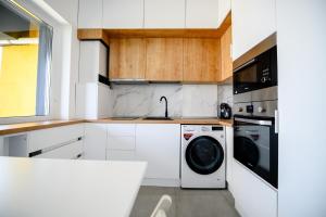 a white kitchen with a washer and dryer at The Lake Spot in Bucharest