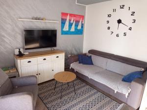 a living room with a couch and a clock on the wall at Sea View Apartment Sunrise Poljica & Blue Lagoon Rent A Boat in Poljica