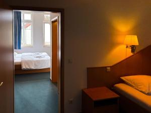 a room with a bedroom with a bed and a window at Stadthotel Kolpinghaus - Vier Ecken in Werne an der Lippe