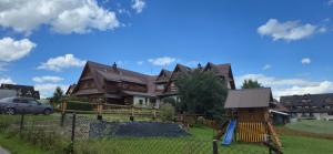 a large house with a playground in front of it at Pokoje gościnne u Krupy in Murzasichle
