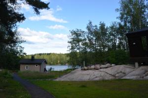 Un pequeño edificio al lado de un lago con una casa. en Villa Jade, en Lohja