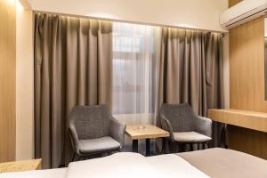 ein Hotelzimmer mit zwei Stühlen und einem Bett in der Unterkunft Michid 2 Hotel in Ulaanbaatar