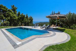 a swimming pool in a yard with an umbrella at Villa Sourouko Xenia beach in Paliouri