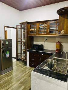 a kitchen with wooden cabinets and a stainless steel refrigerator at Tropical Dream Villa Habarana in Moragaswewa