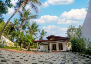 a house with a palm tree in front of it at Tropical Dream Villa Habarana in Moragaswewa