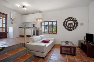 a living room with a white couch and a kitchen at Casa do Pitagudo in Torres Vedras