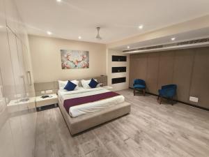 a bedroom with a large bed and a blue chair at Vilva Town House in Chennai