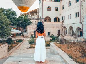a woman in an orange shirt and white skirt walking down a building at Turbel Cave House in Avanos +19 photos