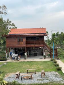 Una casa de madera con dos bancos delante de ella. en BanYat Farm Stay, 