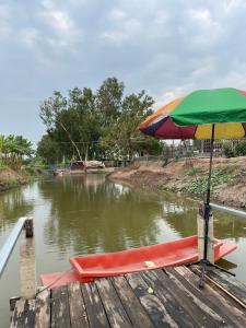 a boat with a colorful umbrella on a river at BanYat Farm Stay in Ban Bang Phae +16 photos