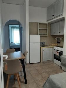 a kitchen with a table and a white refrigerator at Romantza δωμάτιο 4 in Mérikhas +2 photos