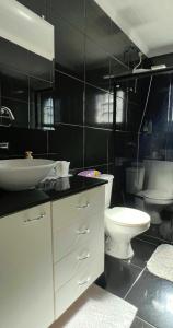 a bathroom with a white sink and a toilet at Refúgio na Capital in Curitiba