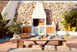 a table with a bowl of fruit on it in front of a stone wall at Paulanni in Teulada