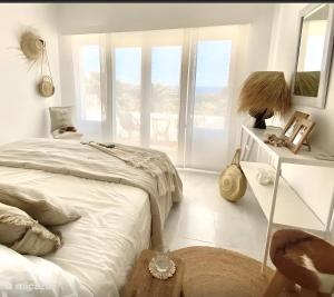 a bedroom with a bed and a table and windows at Paulanni in Teulada