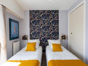 two beds in a room with yellow pillows at Ty Fox by Madame est Servie in Perros-Guirec