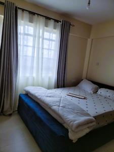 Una cama en un dormitorio con ventana. en 2 Bedroom in Nairobi, en Nairobi