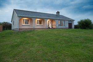 a small white house on a grassy field at Willan Cottage in Portrush