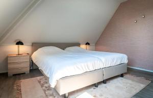 Un dormitorio con una gran cama blanca y dos lámparas. en T-4 Hoeve Holland, en De Cocksdorp
