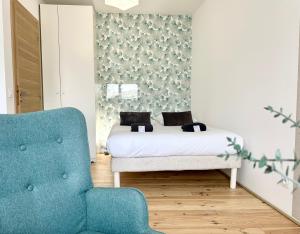 Un dormitorio con una cama y una silla azul. en La Scène de Molière - Neuf - Clim - Central - Fibre, en Mont-de-Marsan 6 fotos más