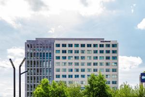 Un edificio alto y blanco con árboles delante. en easyHotel Paris Nord Aubervilliers, en Aubervilliers