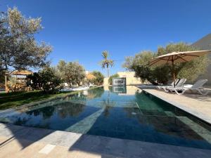 a swimming pool in a resort with an umbrella at Résidence Jamila Location Appartements confort piscine proche zone touristique in Midoun