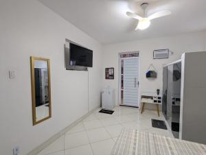 a white living room with a television and a mirror at Oscar Place in Aracaju