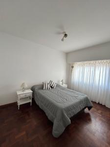 a bedroom with a bed and two tables and a window at EMBE DEPARTAMENTO Necochea in Necochea