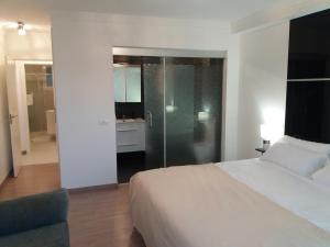 a bedroom with a white bed and a glass shower at Apartment 3 Bedrooms Heated Pool in Adeje +26 photos