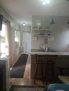 a kitchen with a sink and two bar stools at Recanto das Videiras in Maria da Fé
