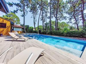 ein Swimmingpool mit Stühlen auf einem Holzdeck in der Unterkunft Villa Villa les Verdiers by Interhome in Biscarrosse