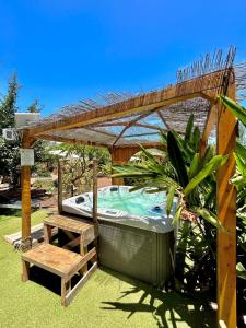 a hot tub under a wooden pergola with a bench at El Refugio de Las Vegas in Valsequillo