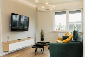un salon avec un canapé et une télévision dans l'établissement Apartament Komfort, à Uniejów