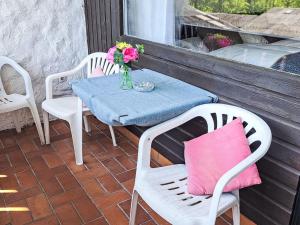 una mesa y sillas en un porche con un jarrón de flores en Apartment Wohnung 413 Bergblick by Interhome, en Strobl