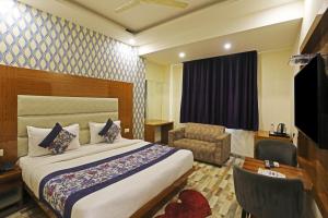 una stanza d'albergo con un letto, una sedia e una televisione di Hotel Smart Lax a Nuova Delhi