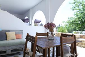 a wooden table with chairs and a vase of flowers at Niriides rooms in Kionia