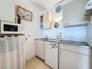 a small kitchen with white cabinets and a microwave at Studio Mer & Soleil-3 by Interhome in Saint-Brévin-lʼOcéan +12 photos